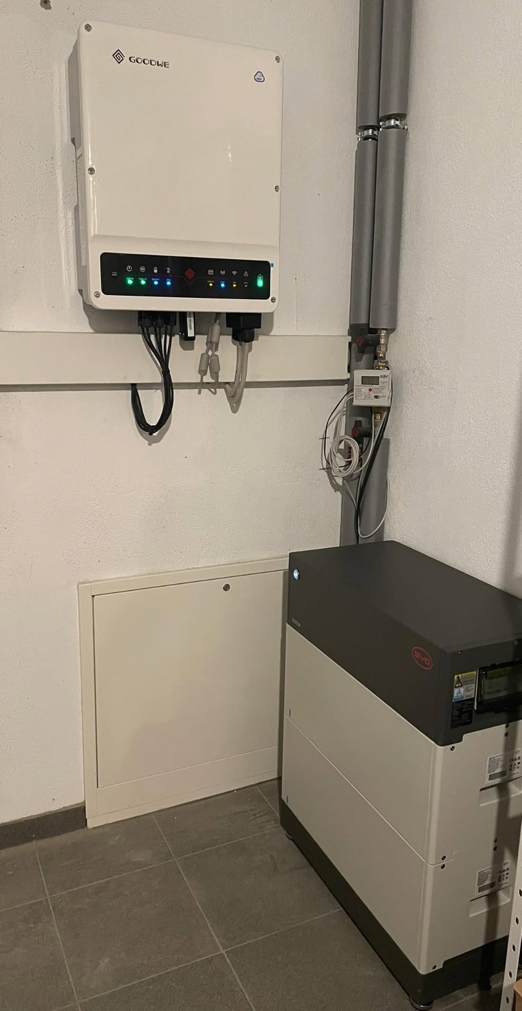 An der Wand montierter GoodWe-Hybridwechselrichter, daneben ein BYD-Batteriespeicher im Technikraum